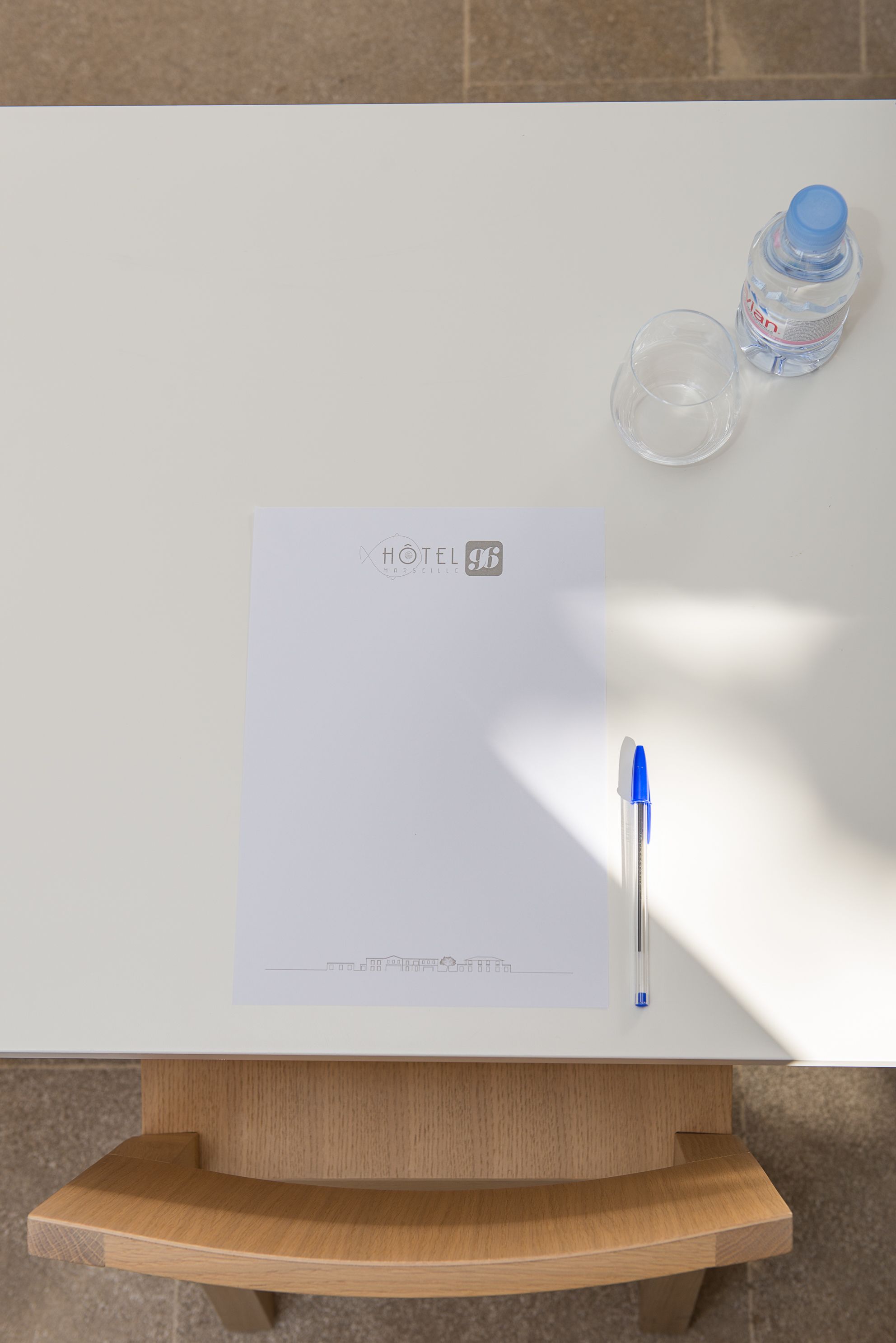 Een whiteboard met een hotel logo, een pen en een waterfles op een houten tafel.