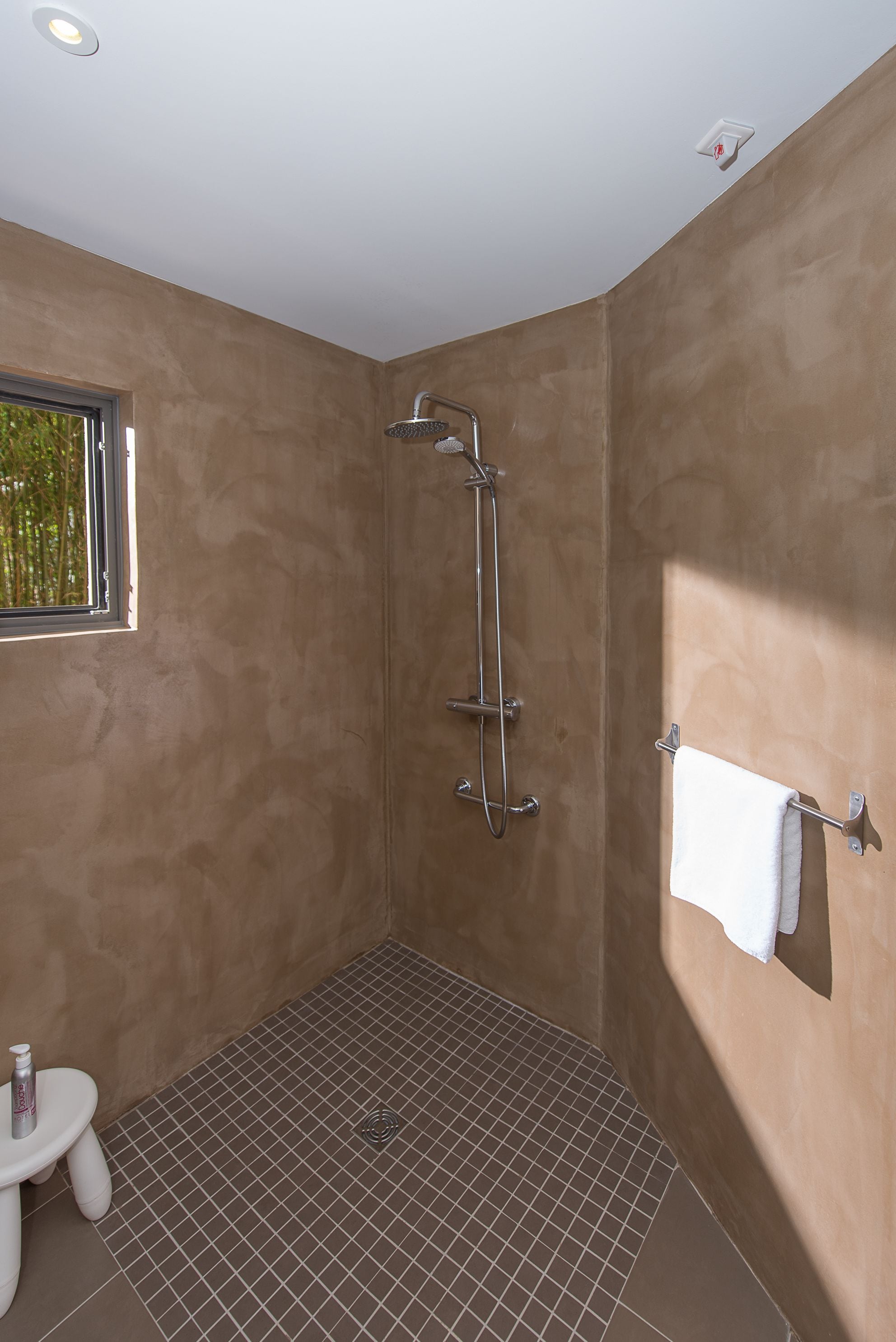 A bathroom with a shower, a window, and a towel rack.
