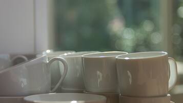 A stack of white ceramic mugs on a wooden table near a window.