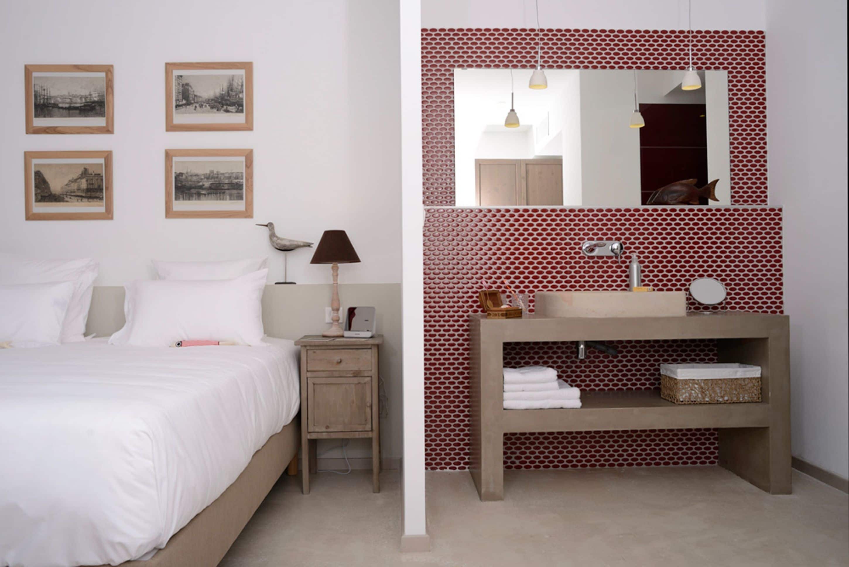 Une chambre à coucher avec un lit, une table de chevet, une lampe et des tableaux accrochés au mur.