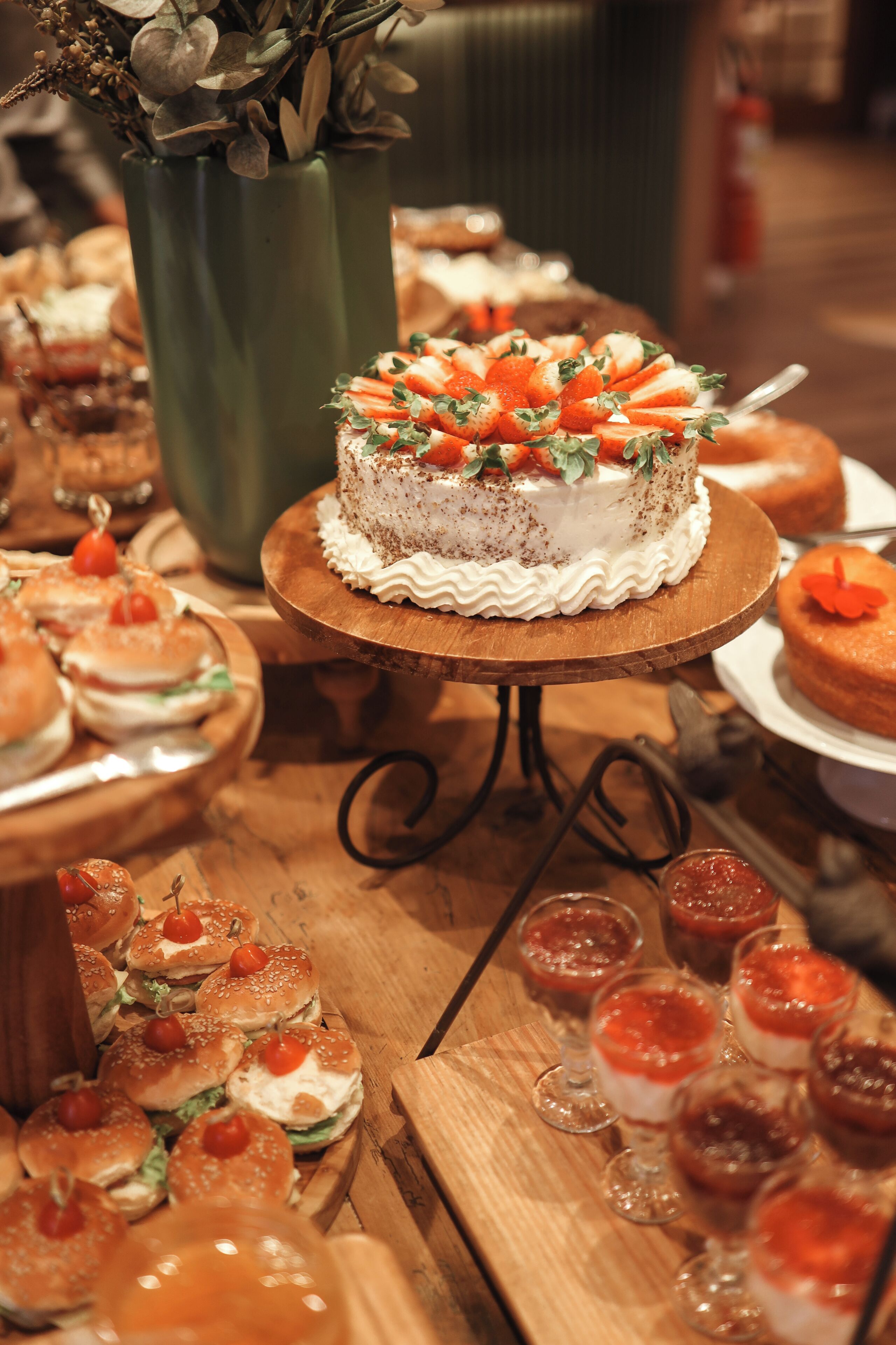A dessert table with a cake, sandwiches, and small desserts.