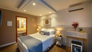 Habitación de hotel con una cama grande, mesitas de noche con lámparas, un refrigerador pequeño y un tocador con espejo.