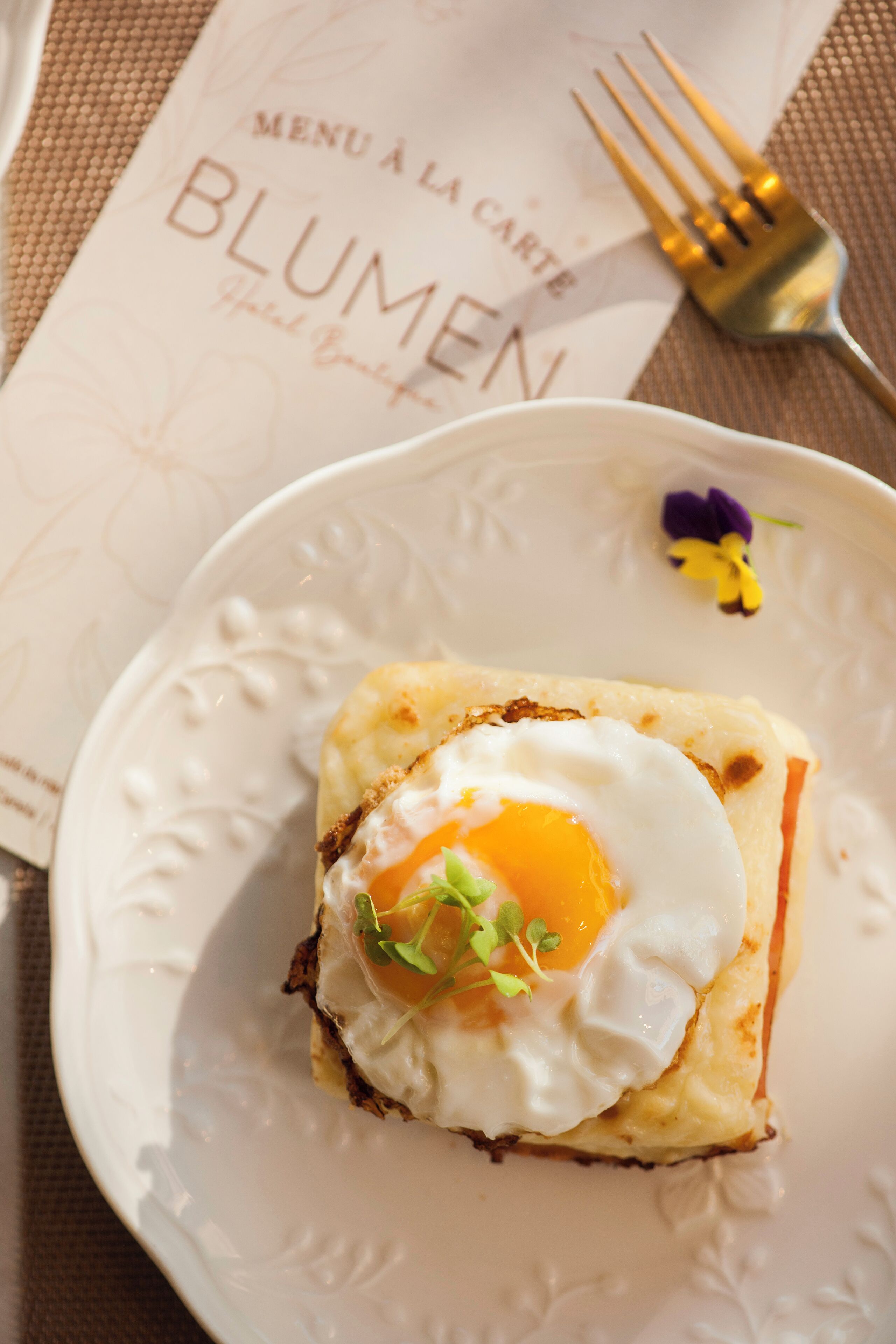 Un plato con comida para el desayuno, un menú y un tenedor sobre una mesa.