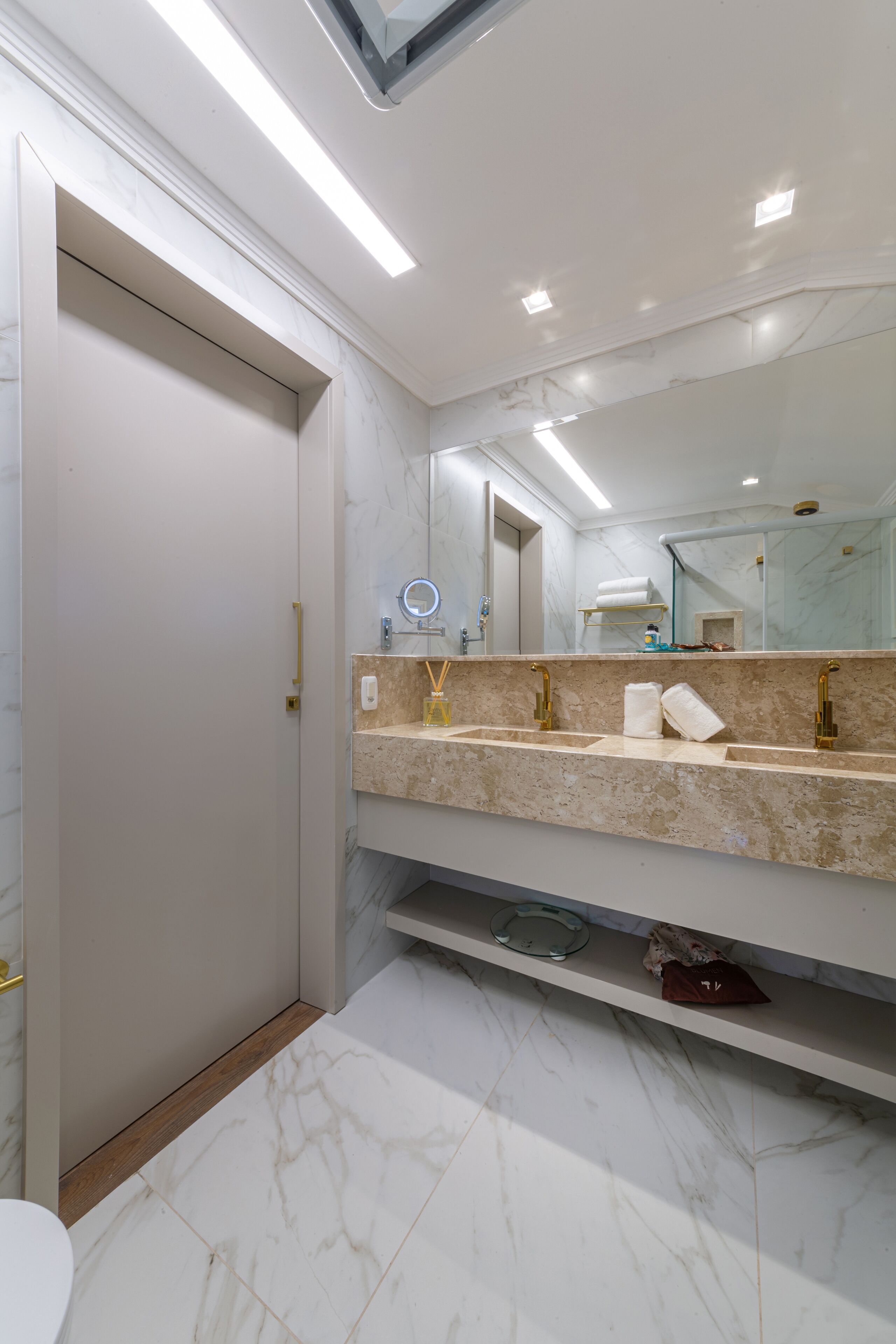 Un baño moderno con tocador de mármol, un espejo grande y un inodoro.