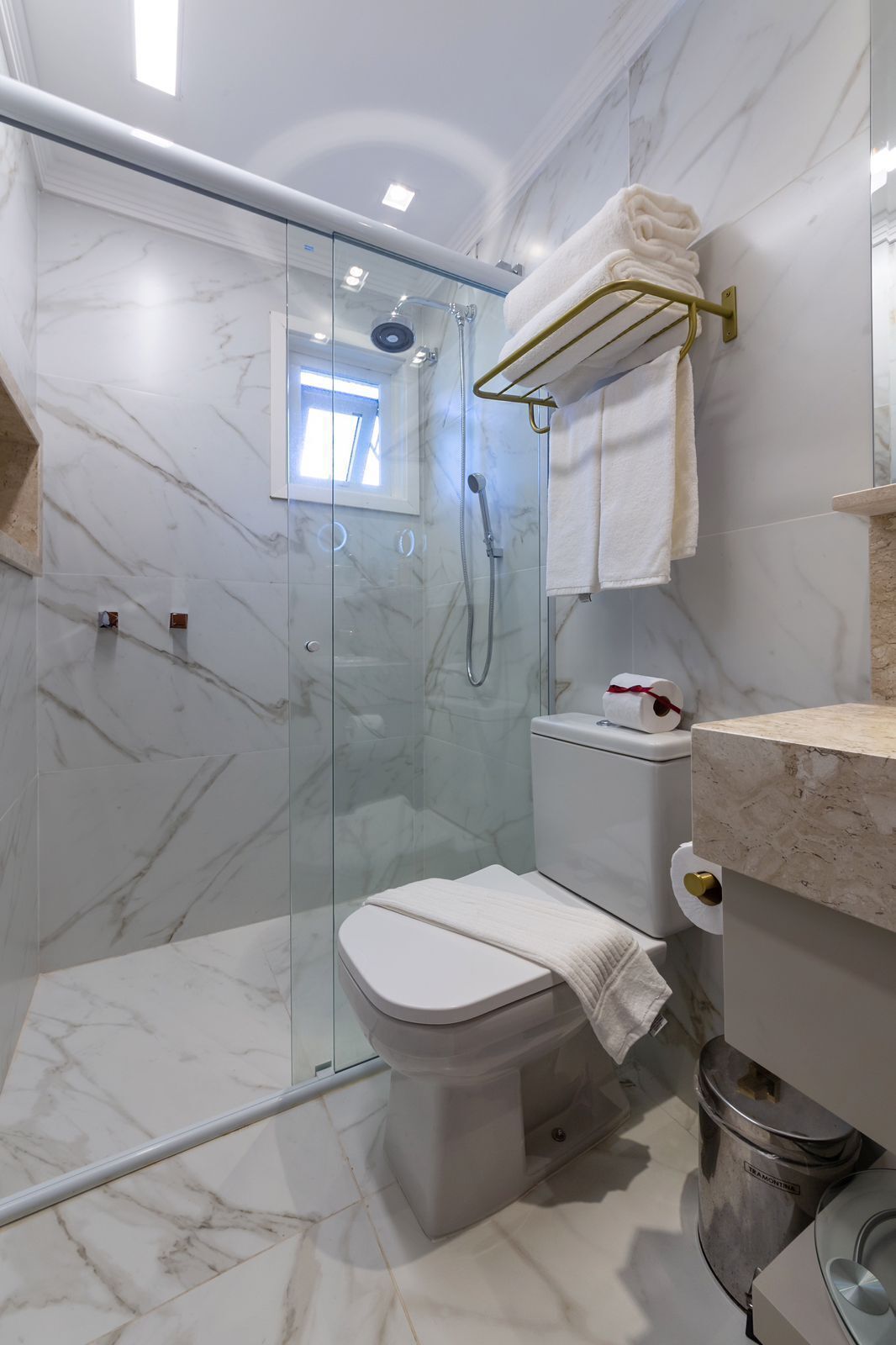 Un baño moderno con ducha de vidrio, inodoro y suelo de mármol.