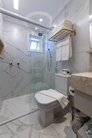 Un baño moderno con ducha de vidrio, inodoro y suelo de mármol.