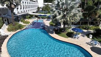 Una piscina al aire libre, sombrillas, sillones reclinables de piscina