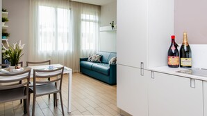 En modern lägenhet med ett matområde, en turkosfärgad soffa och en köksbänk med två vinflaskor.