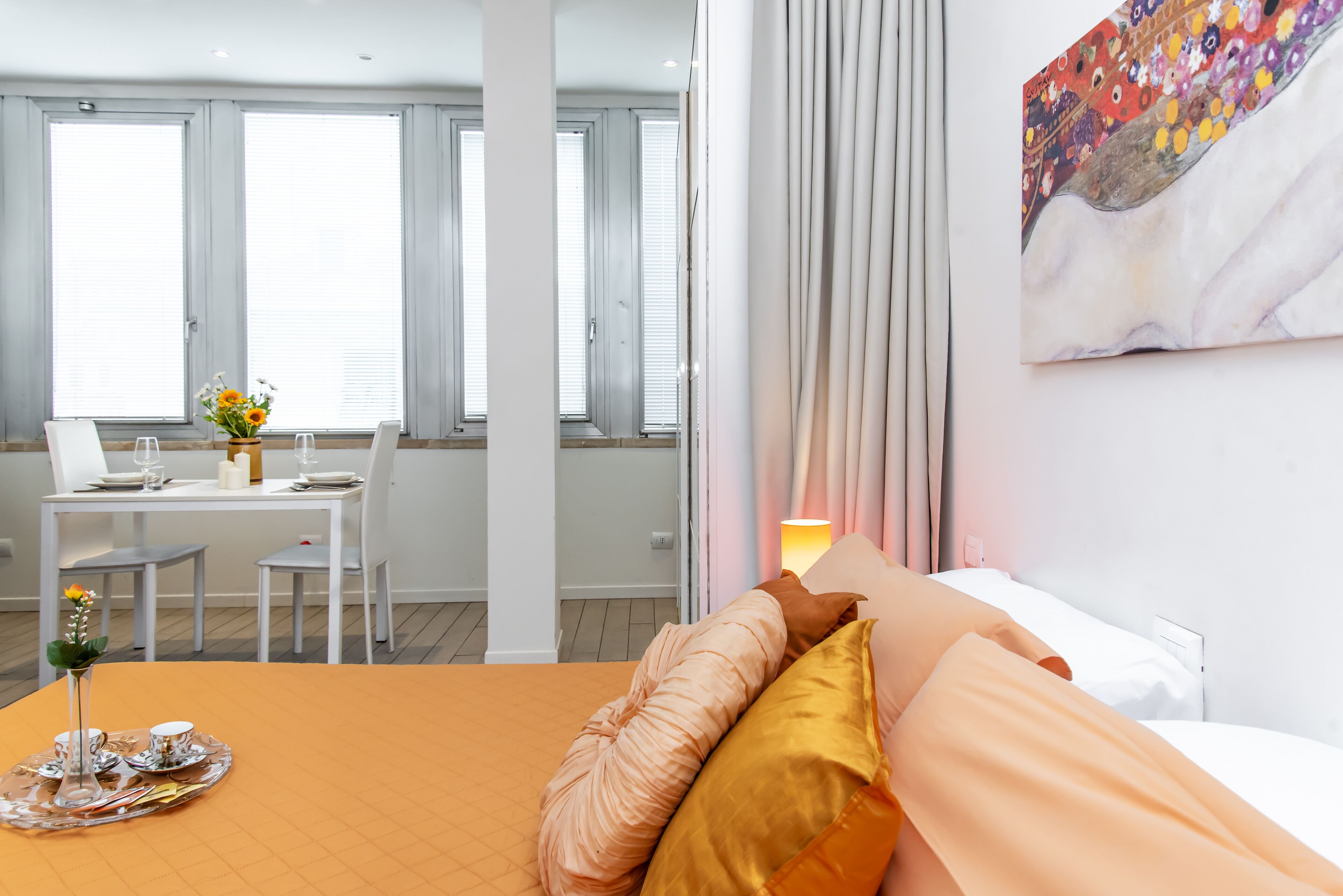 Une chambre d’hôtel avec un lit, une table à manger et des chaises, et un tableau accroché au mur.
