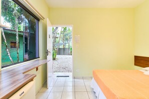 Un dormitorio con una cama, una ventana y una puerta que da a un espacio exterior.