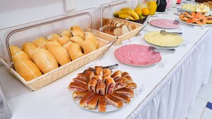 Una mesa de buffet con diferentes alimentos, incluyendo pan, embutidos y frutas.
