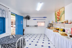 Una habitación con una mesa de comedor, un ventilador y un bufé con diversas opciones de comida.