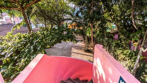 Una escalera roja que conduce a un área techada, con un letrero que indica una dirección descendente y un símbolo de rayo.