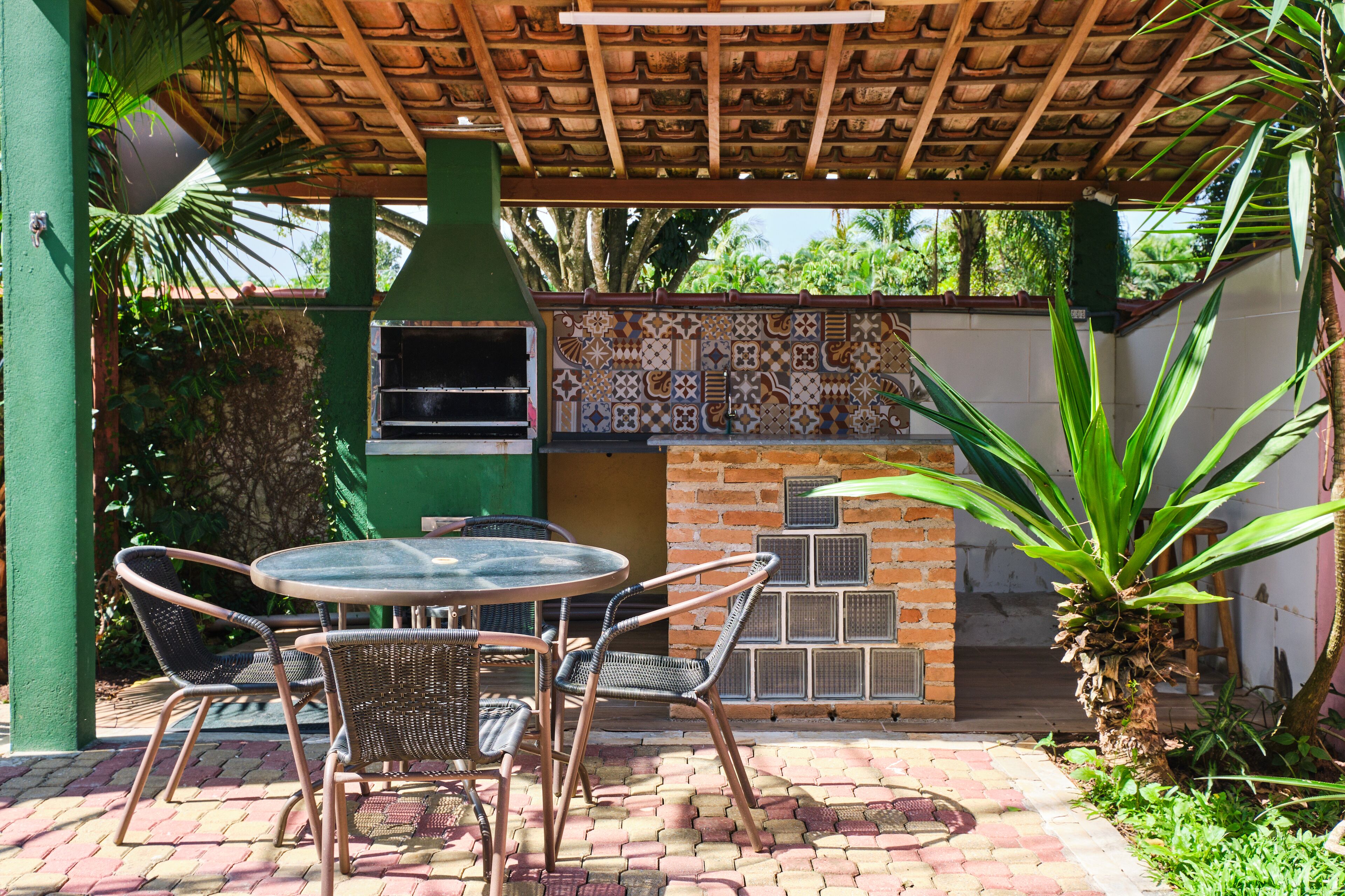 An outdoor patio with a brick wall, a grill, and a table with chairs.