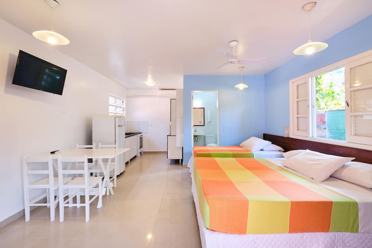 A hotel room with a bed, a desk, chairs, a TV, and a window.