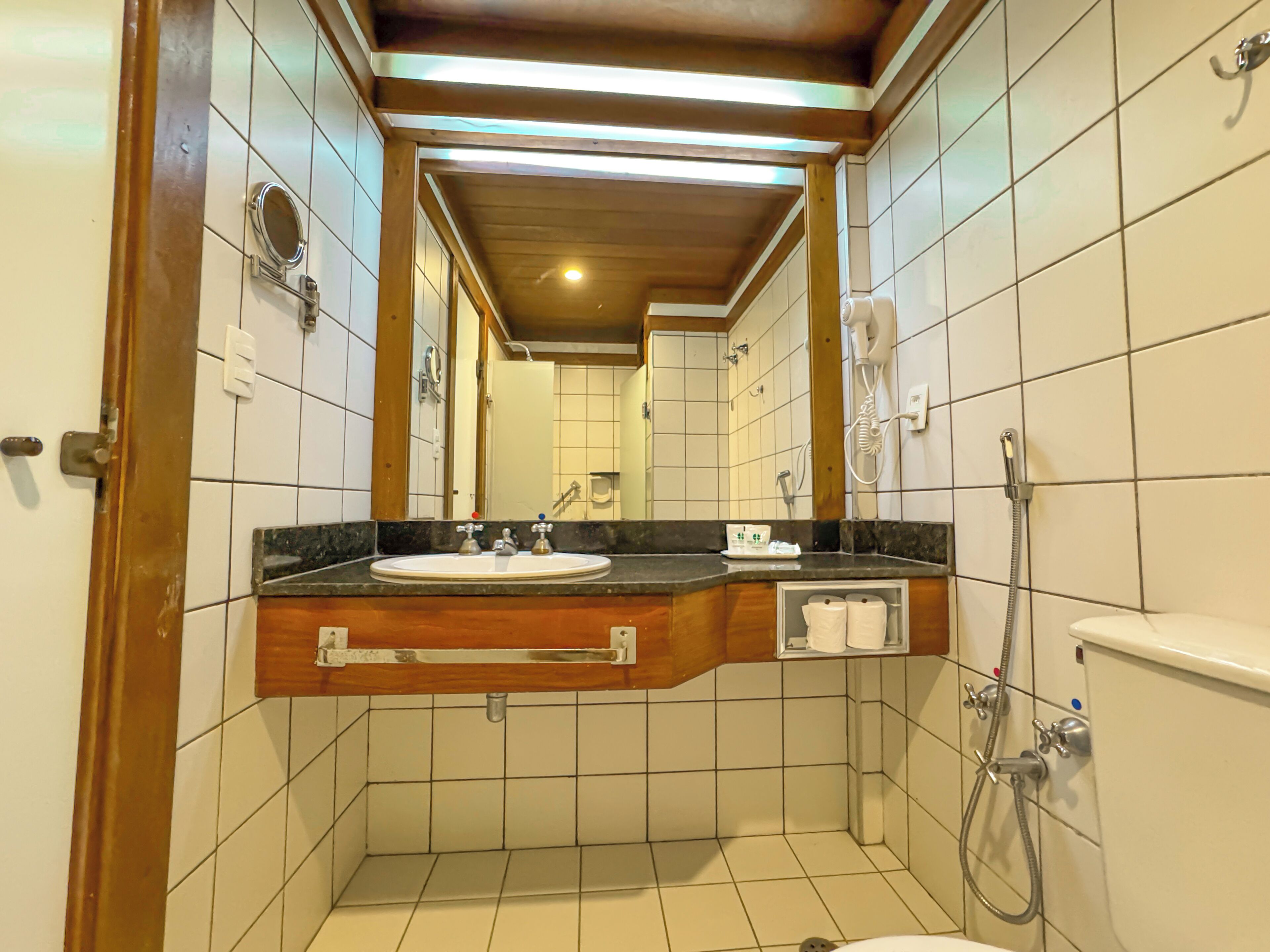 A bathroom with a sink, mirror, and shower.