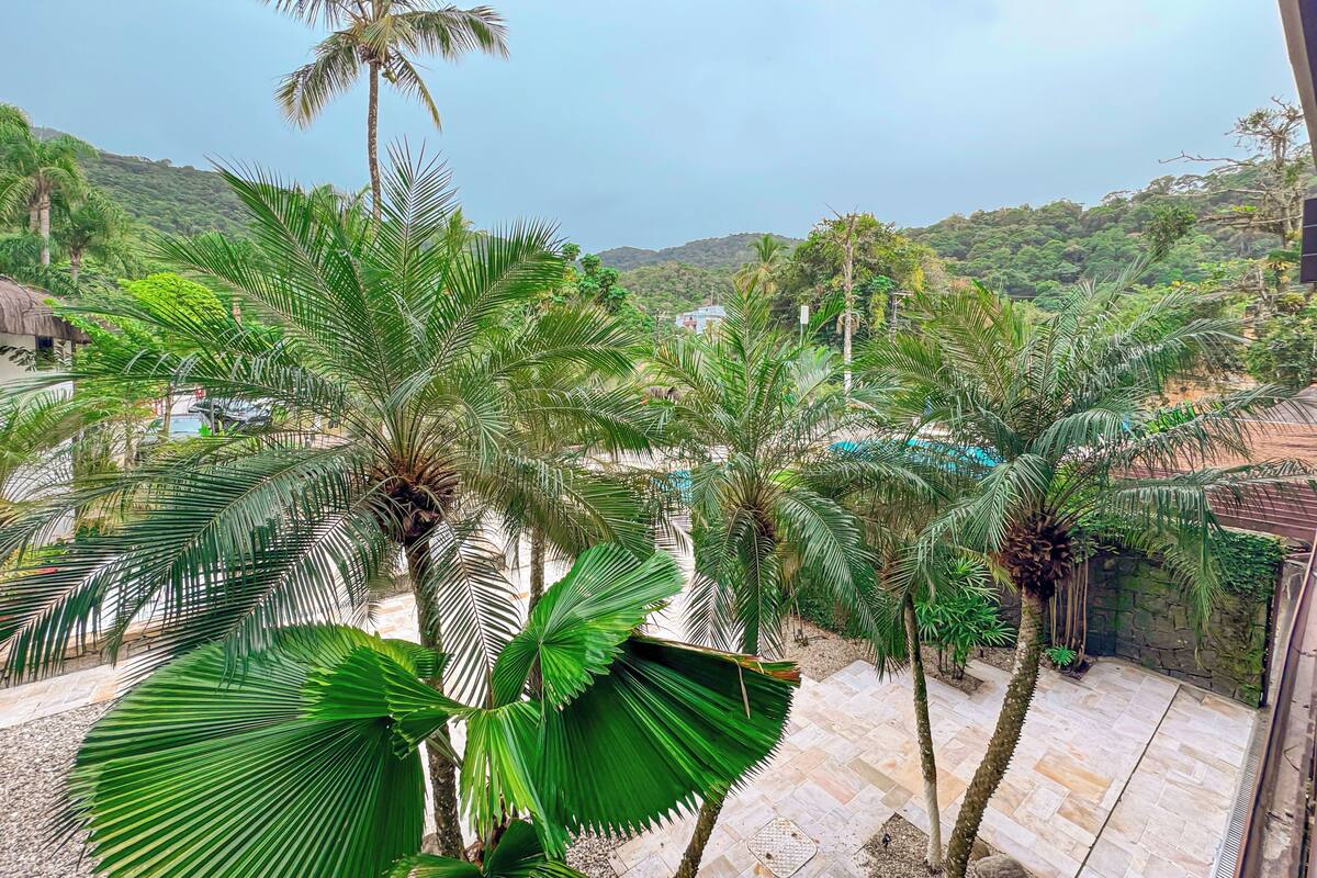 A lush garden with palm trees and a pool area.