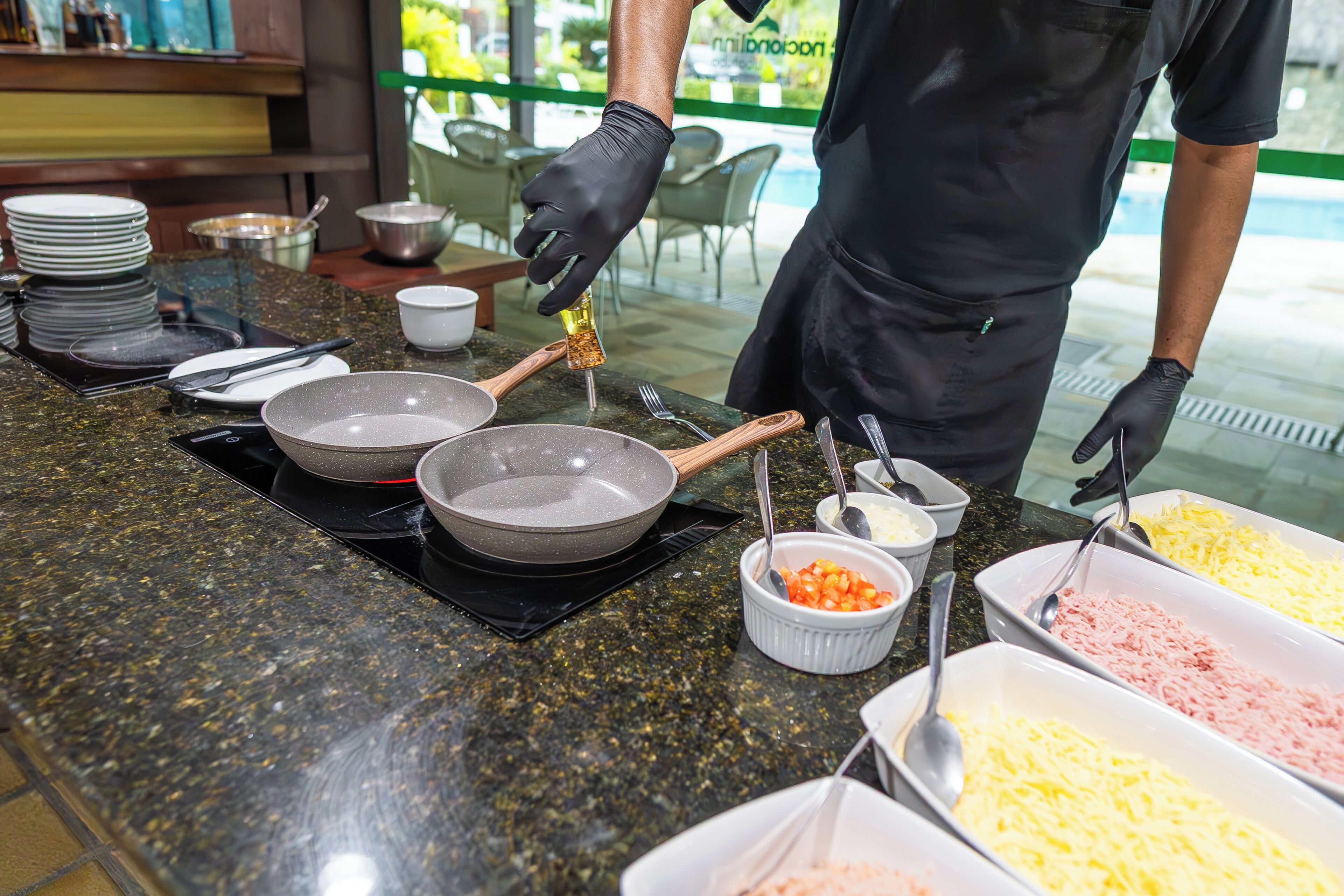 A buffet setup with various food items and utensils on a granite countertop.