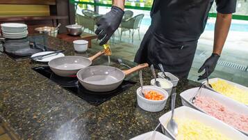 A buffet setup with various food items and utensils on a granite countertop.