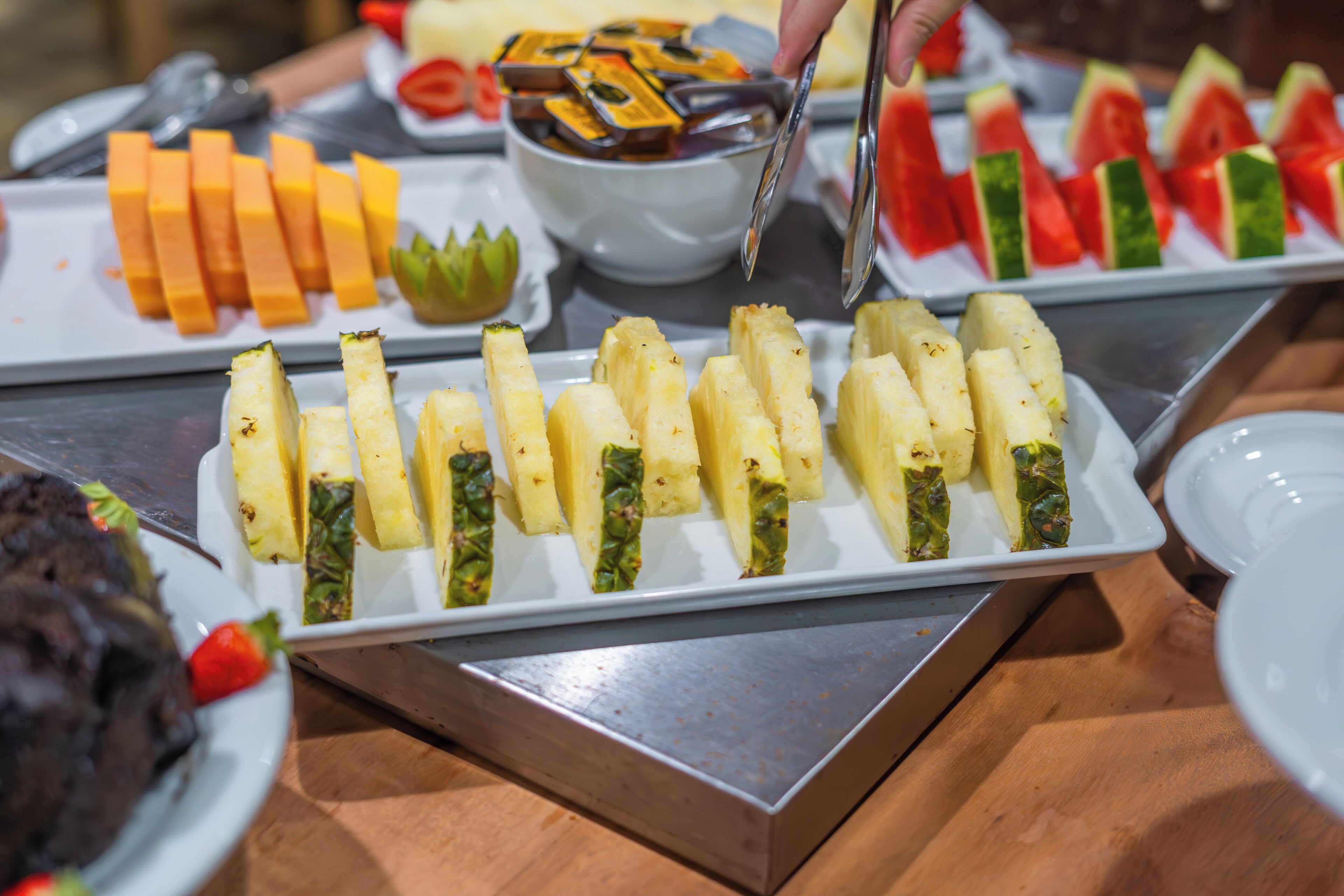 Buffet com diversos alimentos, incluindo frutas e legumes fatiados.