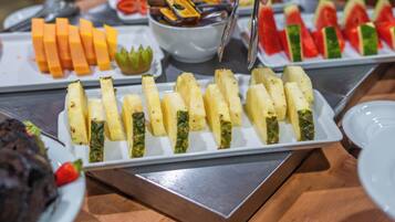 Buffet com diversos alimentos, incluindo frutas e legumes fatiados.