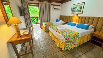 A hotel room with two beds, a desk with a lamp, a TV, and an air conditioning unit.