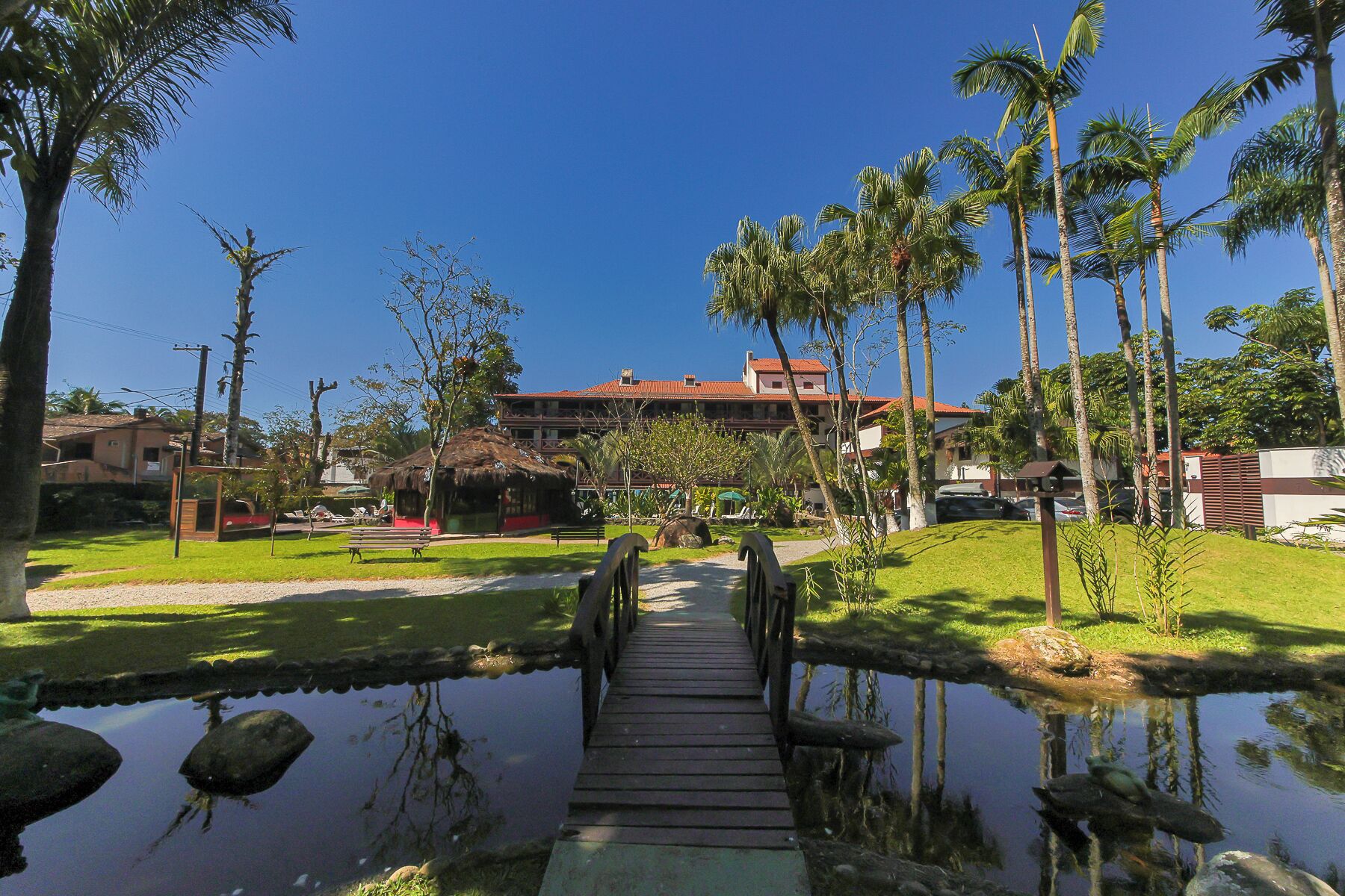 A wooden bridge over a pond with a building in the background.