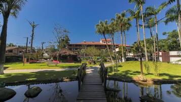 A wooden bridge over a pond with a building in the background.