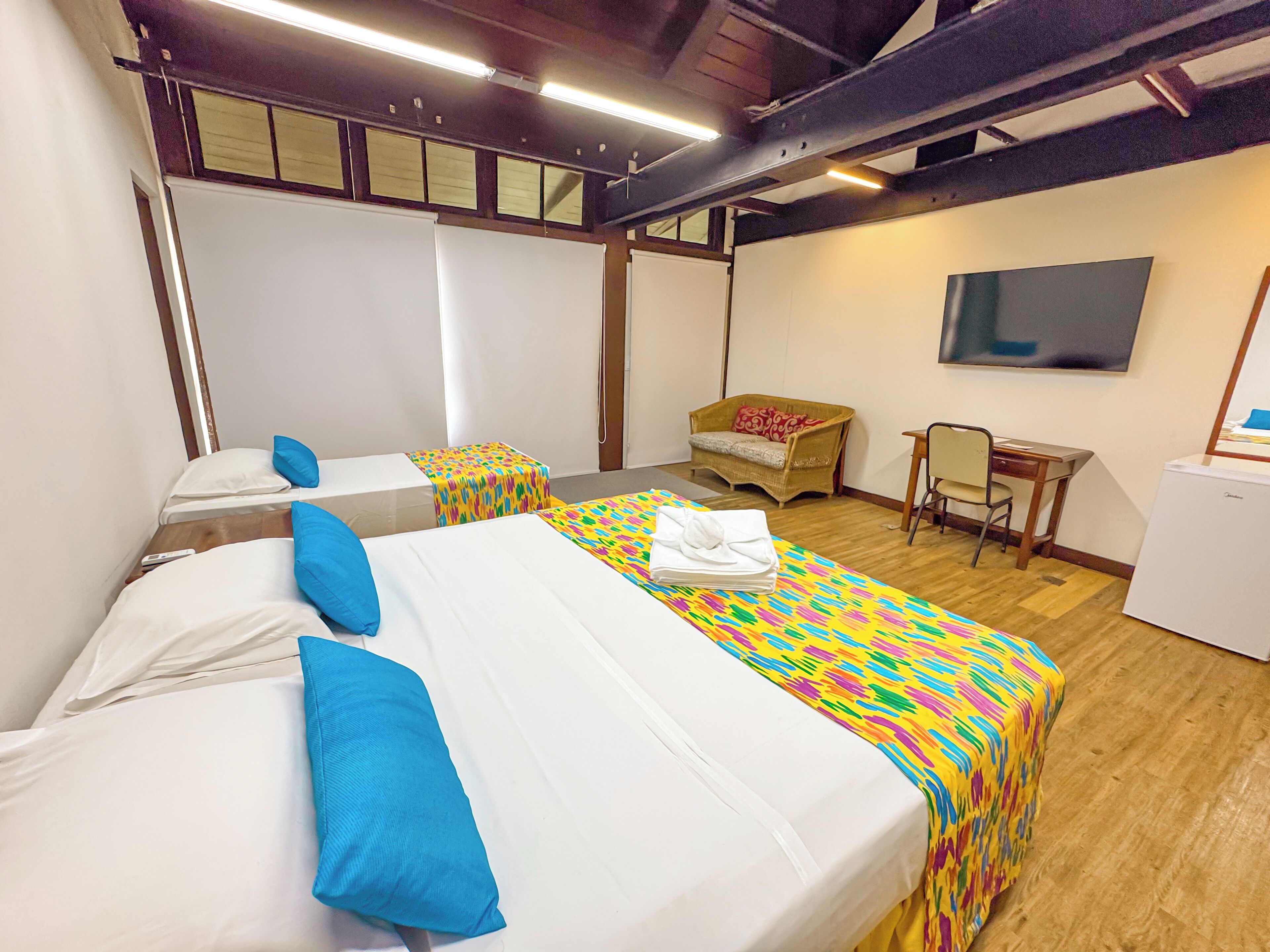 Quarto de hotel com duas camas, televisão, escrivaninha e uma cadeira.