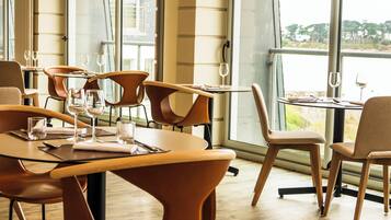 Un restaurante con muebles modernos y amplios ventanales que ofrecen vistas al exterior.