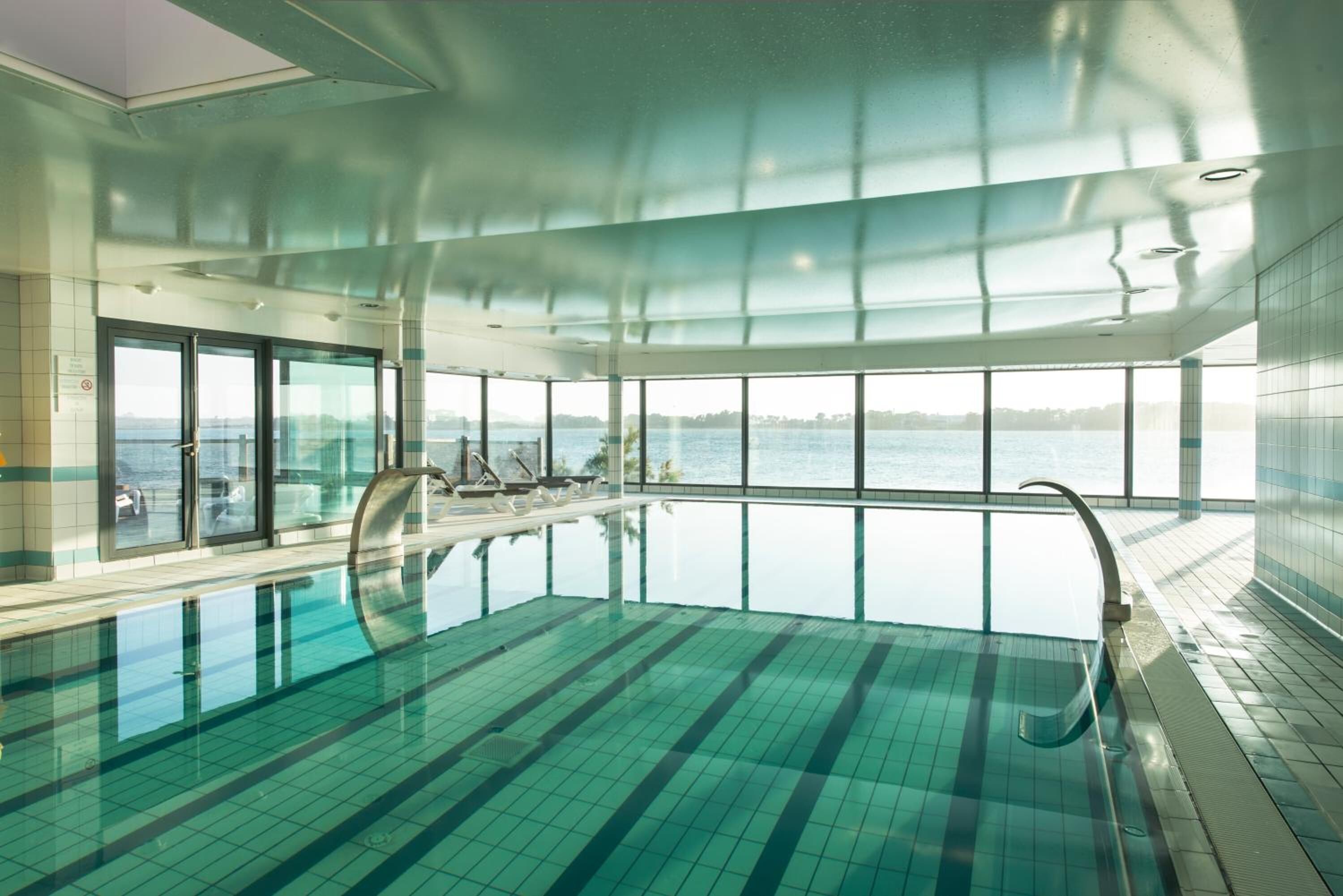 Una piscina interior con vistas claras al mar, ventanas amplias y un diseño moderno.