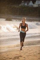 Une personne court sur une plage de sable, avec des vagues en arrière-plan.