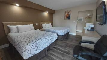 Una habitación de hotel con dos camas, un escritorio, una silla y un televisor.