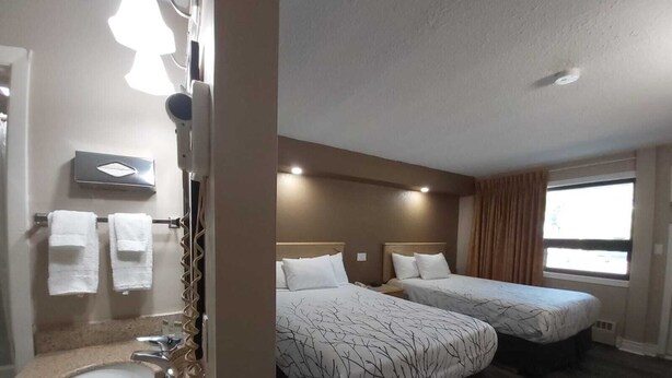 Une chambre d’hôtel avec salle de bain, deux lits, une fenêtre et un lavabo.
