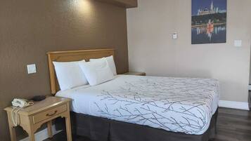 A hotel room with a bed, a nightstand, a telephone, and a painting on the wall.