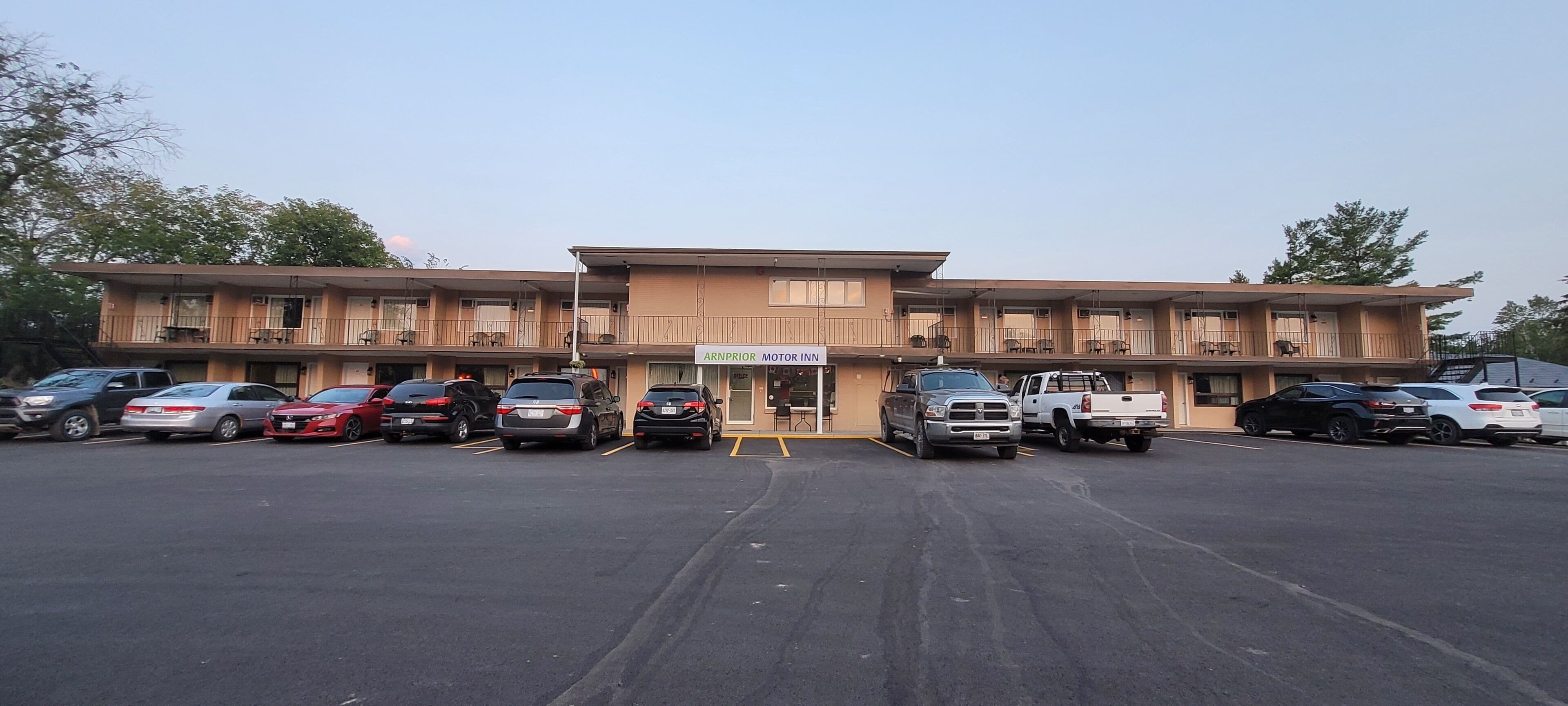 A motel with multiple floors and a parking lot filled with cars.