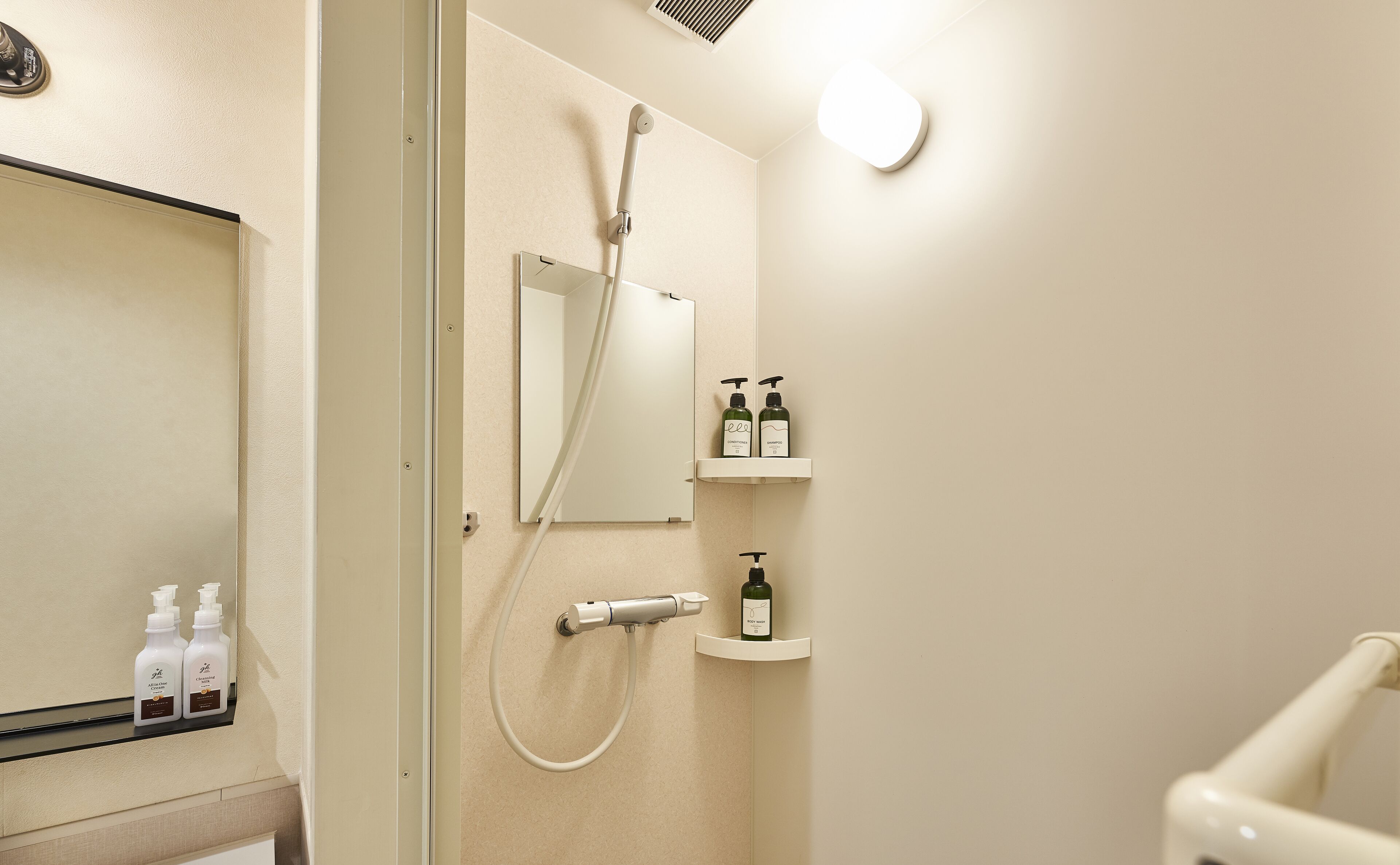 A bathroom with a glass shower enclosure, a mirror, and shelves with toiletries.