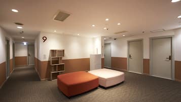 A hotel room with a large bed, a small sofa, a wardrobe, and a desk.