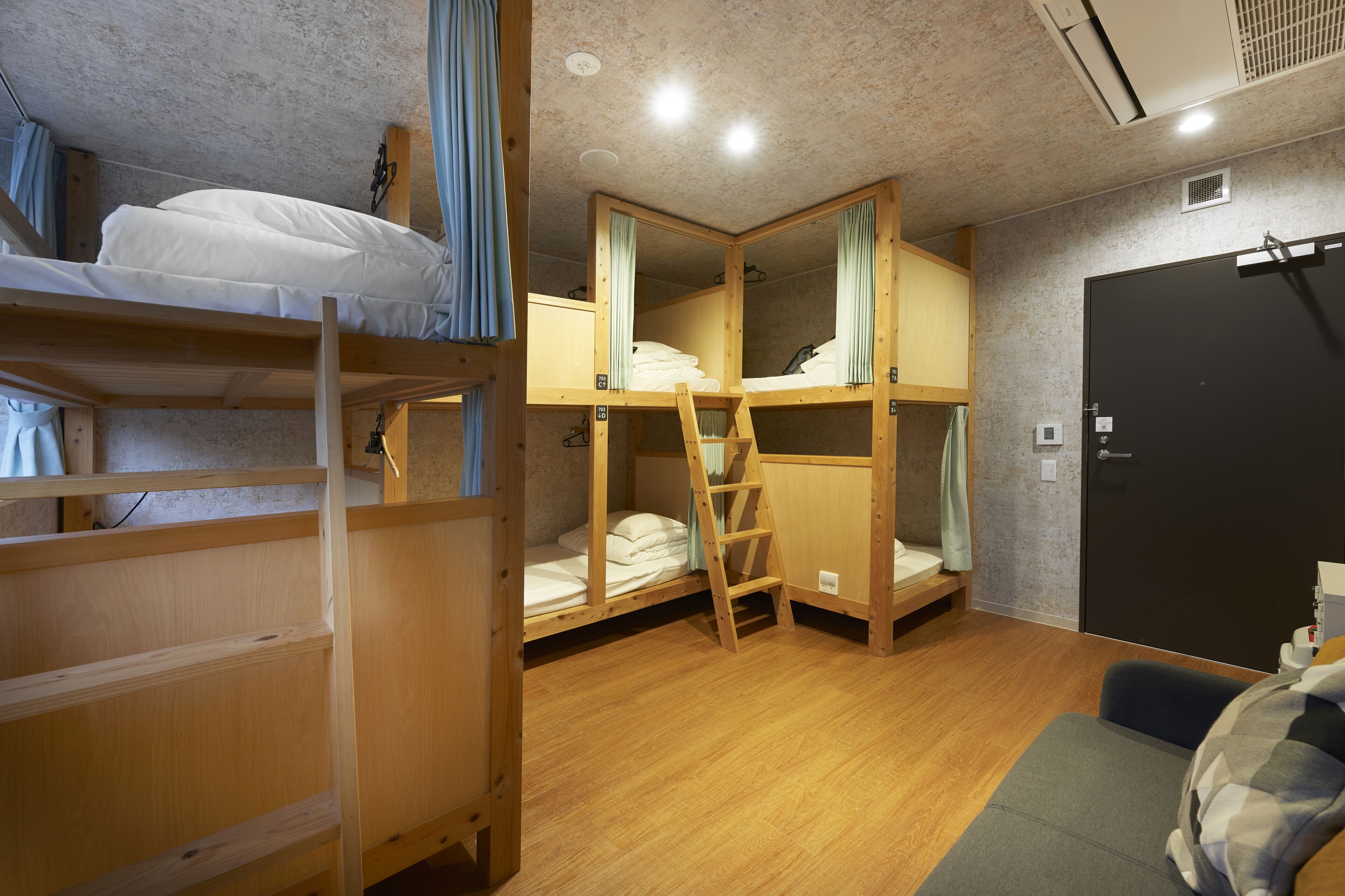 A bunk bed room with wooden bunk beds, a ladder, a desk, and a black door.