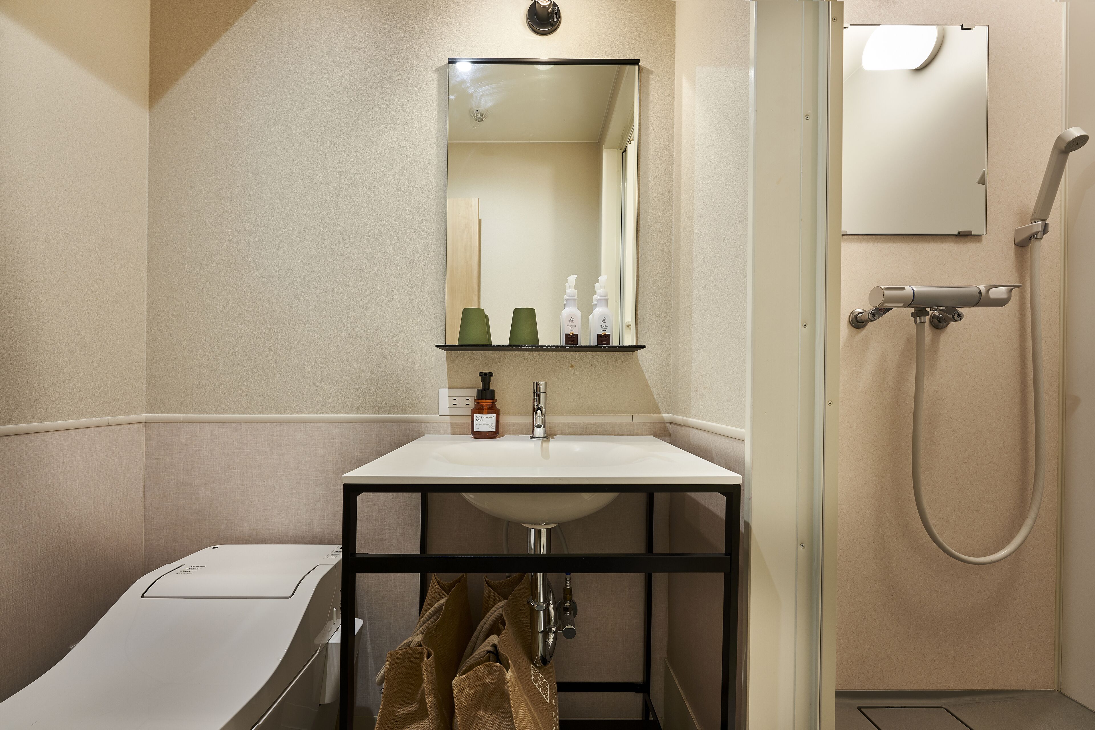Een badkamer met wastafel, spiegel en douche.