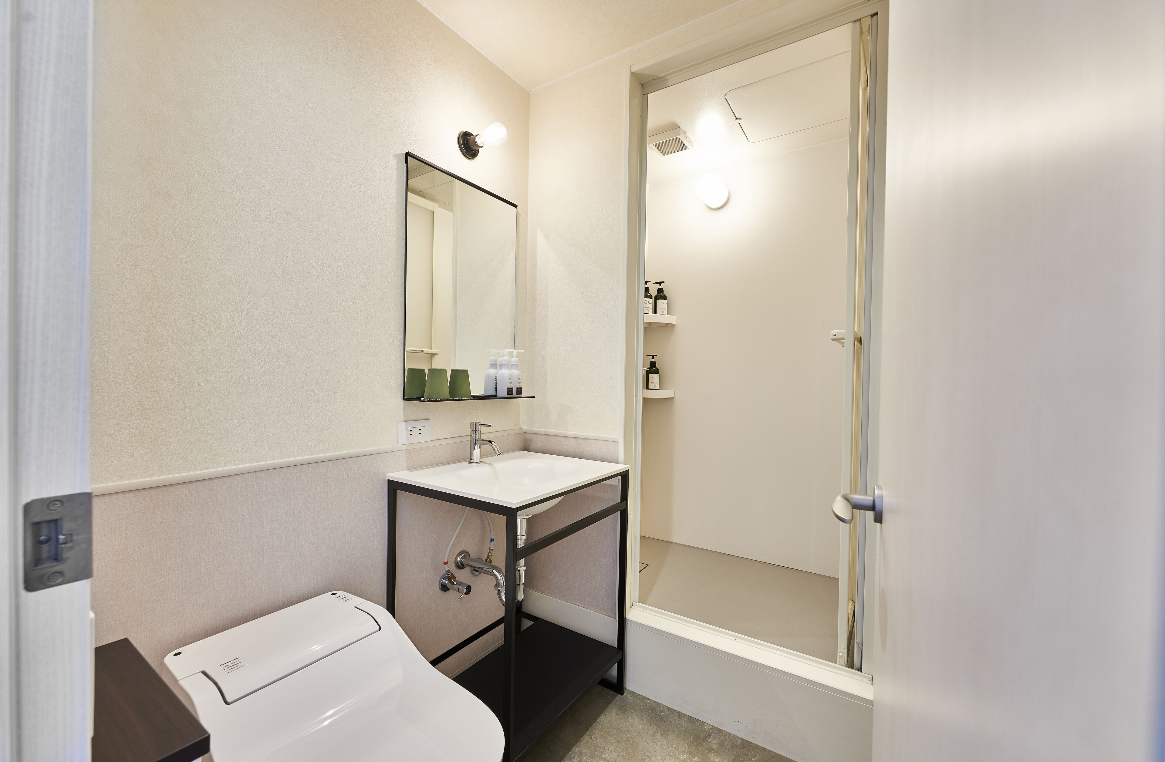 Een badkamer met een witte wastafel, een spiegel, een douche en een toilet.