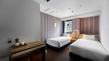 A hotel room with two beds, a desk, a chair, a window, and a nightstand.