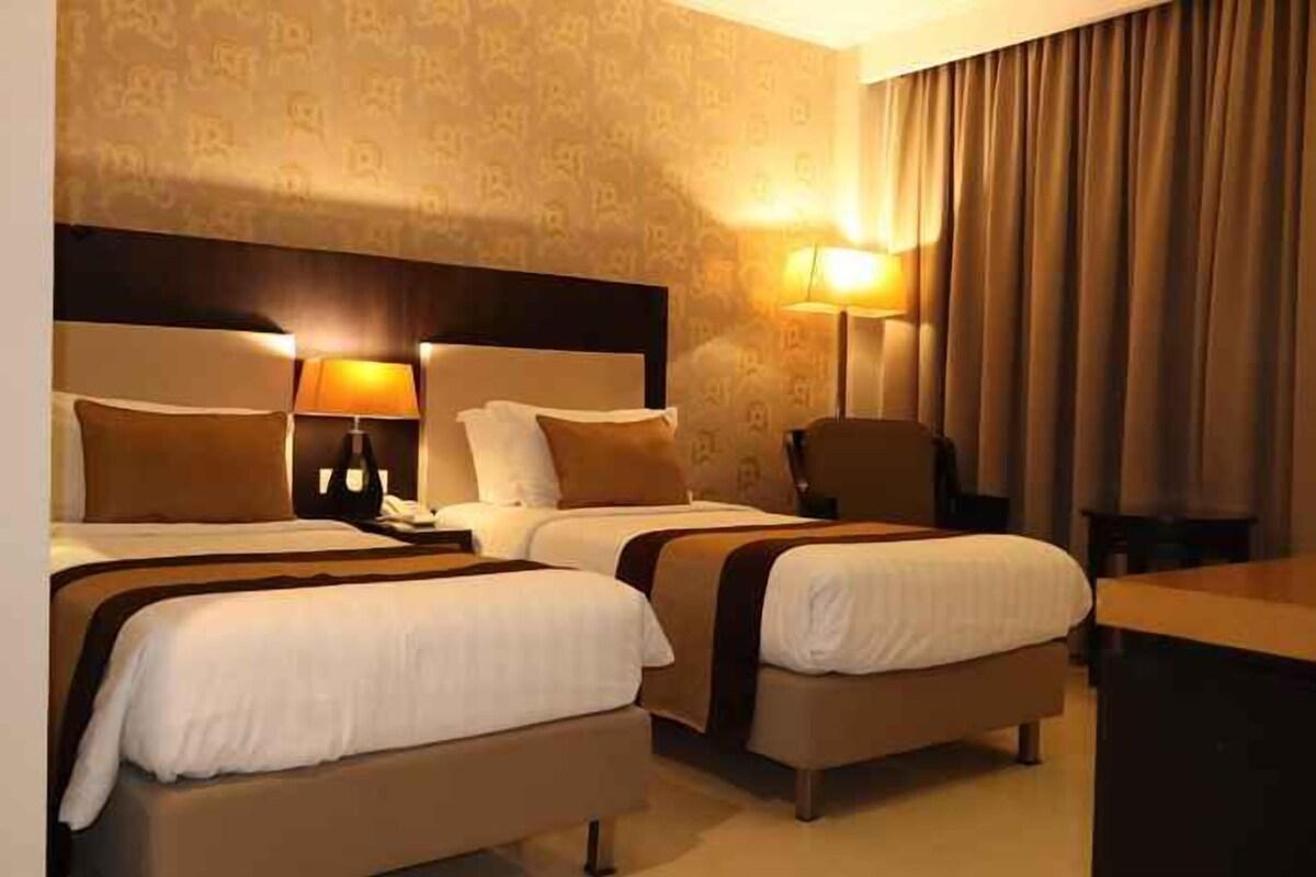 Une chambre d’hôtel avec deux lits, un bureau et une chaise.