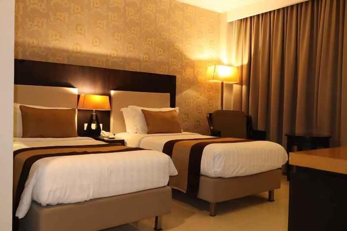 Une chambre d’hôtel avec deux lits, un bureau et une chaise.