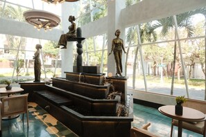 Un intérieur moderne agrémenté d’une fontaine à étages, de coins salon et de grandes fenêtres offrant une vue sur l’extérieur.