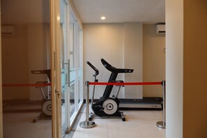Een sportschool met twee loopbanden en een hometrainer, gescheiden door een rode barrière.