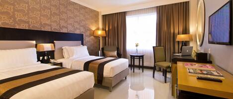 Une chambre d’hôtel avec deux lits, un bureau, une chaise, un ordinateur portable et une télévision.