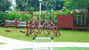 A playground with a climbing structure, a slide, and a netted play area.