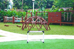A playground with a climbing structure, a slide, and a netted play area.