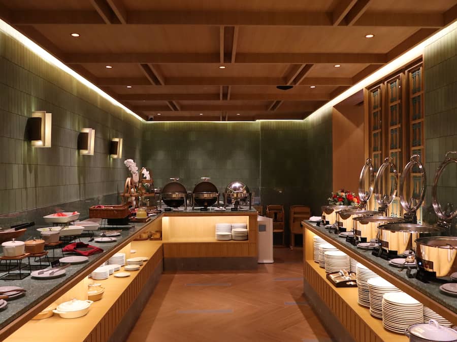 Buffet montado com diversas estações de serviço, um balcão central e uma variedade de pratos e utensílios.